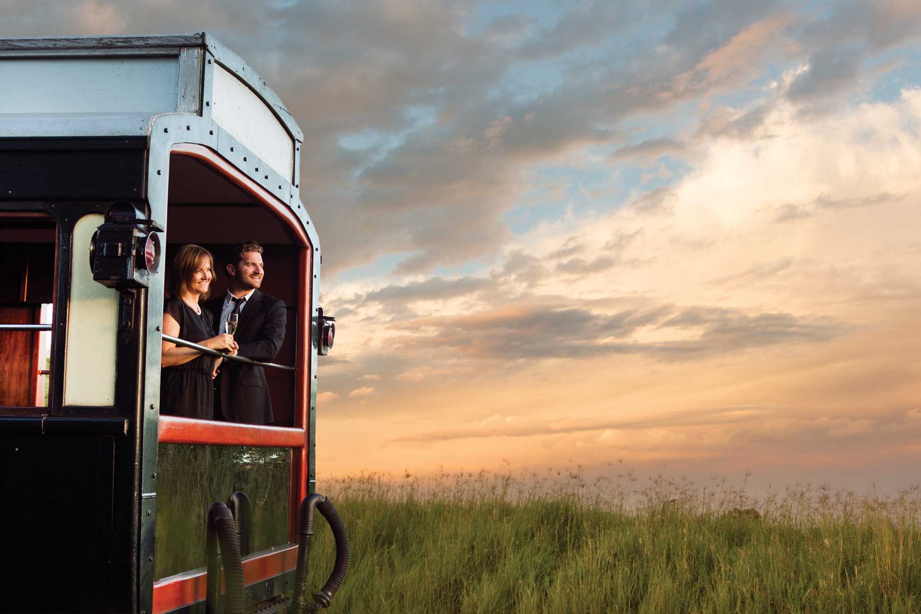 Couple savourant une escapade exclusive à bord d'un train de luxe, profitant de paysages enchanteurs lors d'un voyage sur mesure.