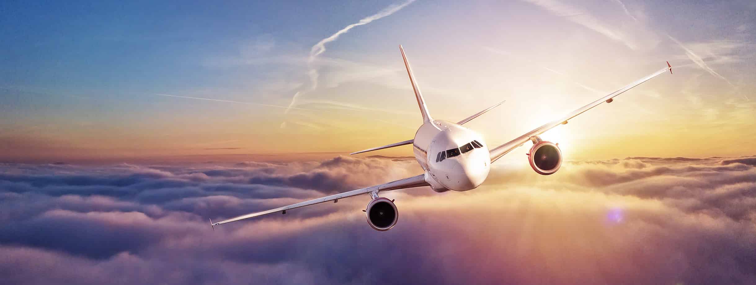 Avion survolant des nuages au coucher de soleil, prêt pour des voyages immersifs avec TMR Voyages vers des destinations iconiques.