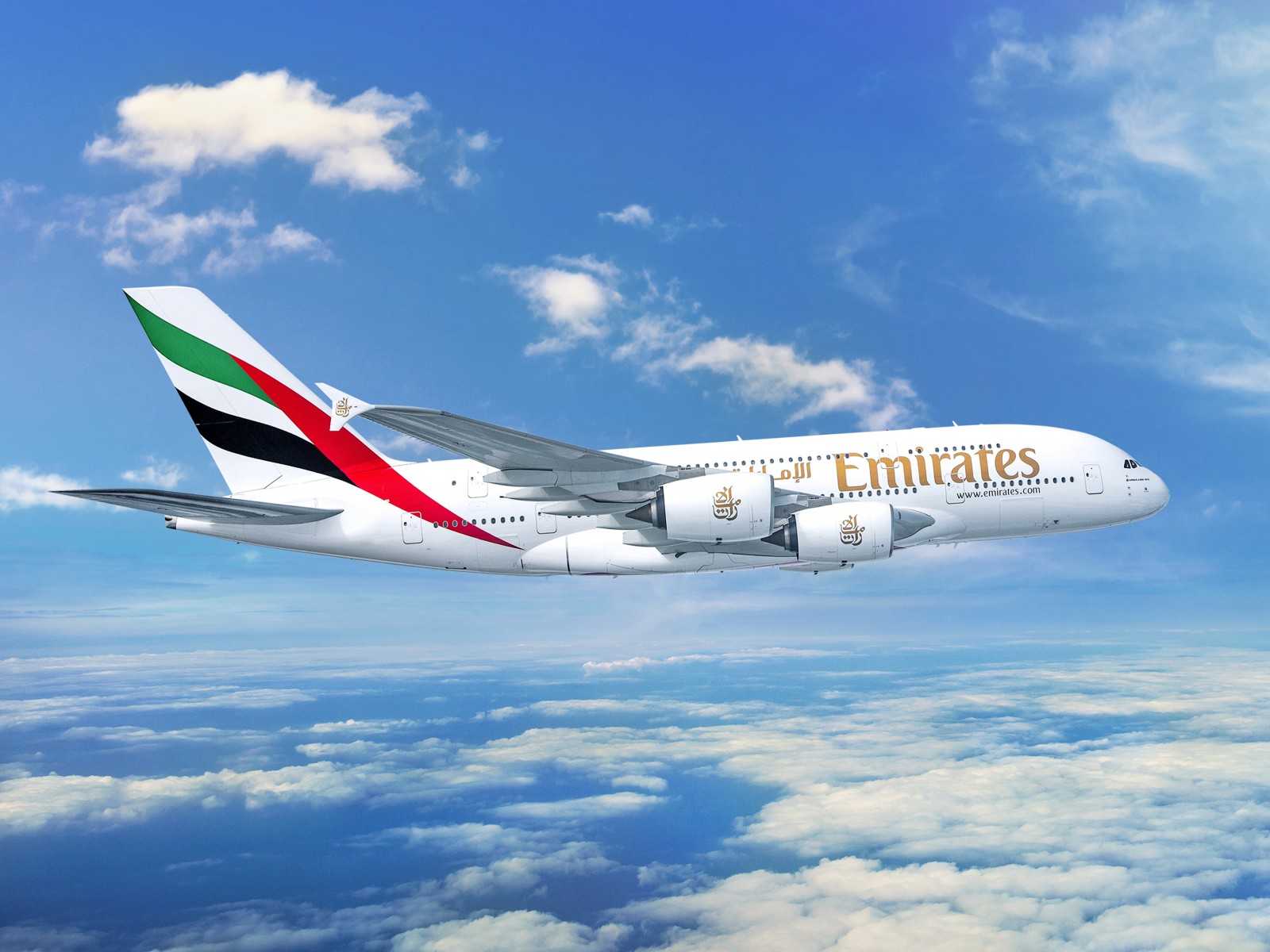Avion Emirates survolant des nuages, symbole des voyages de luxe et d'aventures authentiques avec TMR Voyages.
